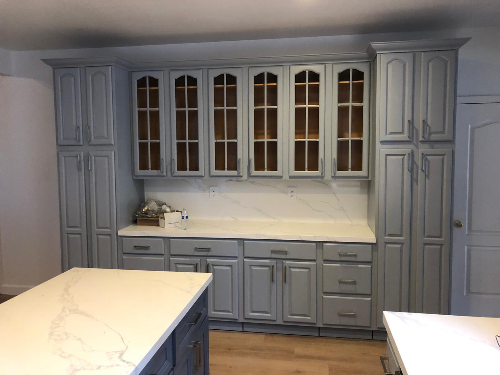 Blue-grey kitchen with glass cabinet doors and quartz countertops in Portland