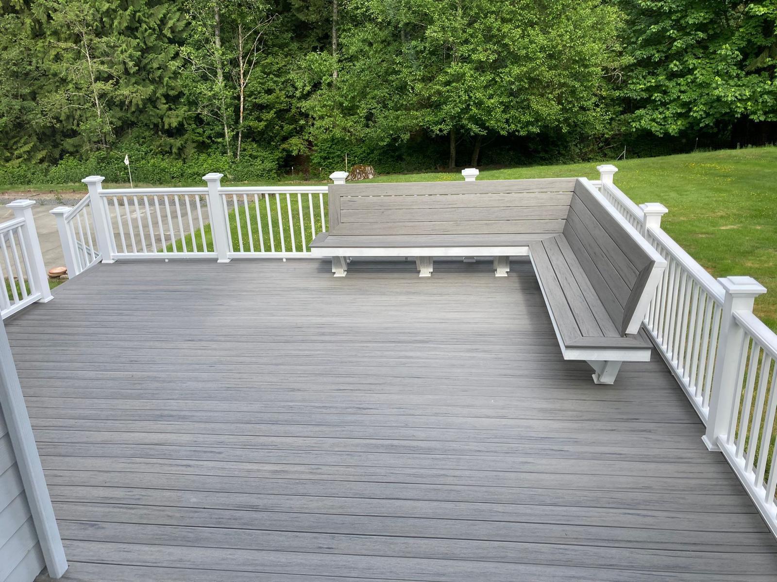 Composite deck with L-shaped bench, white railing and wooded backyard in Portland