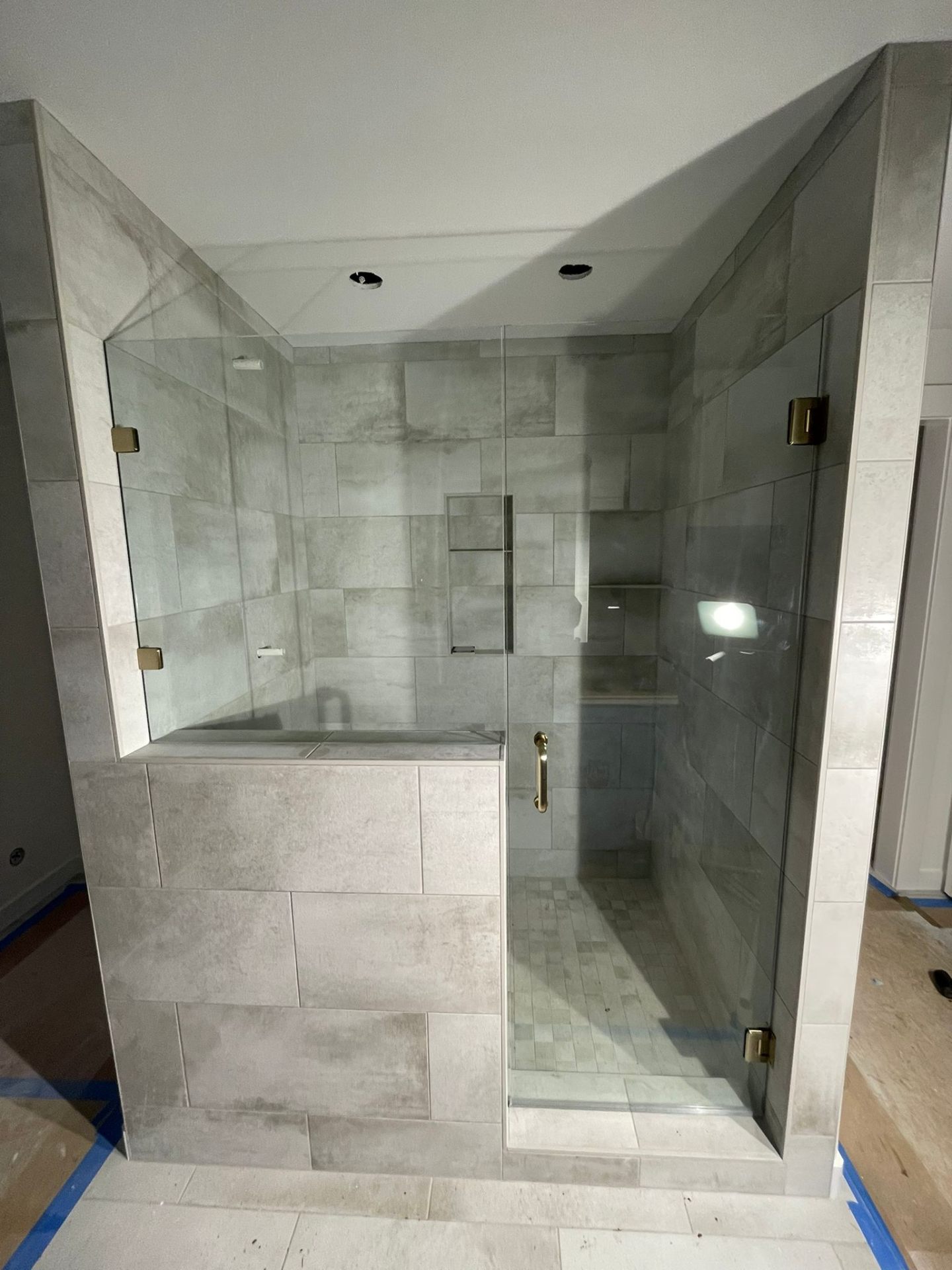 Custom shower with frameless glass door, gray tile and built-in bench in Portland