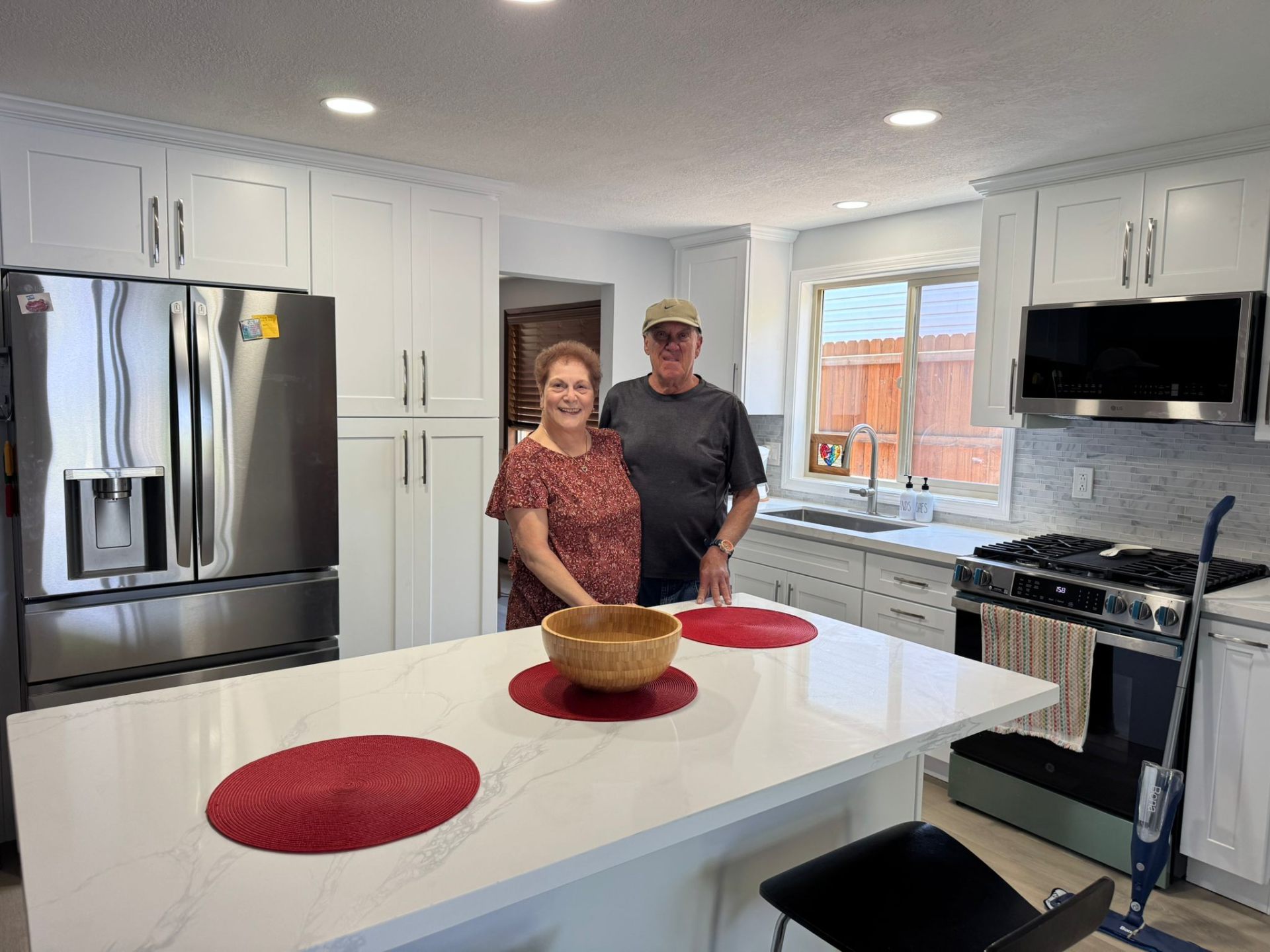 Satisfied clients in their finished kitchen remodel with quartz island and subway tile in Portland