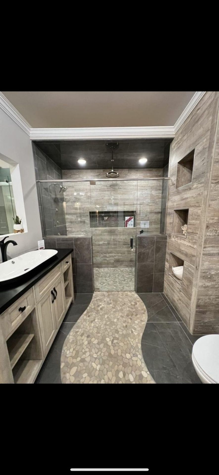 Spa-inspired bathroom with pebble floor, dark tile shower and wood vanity in Portland
