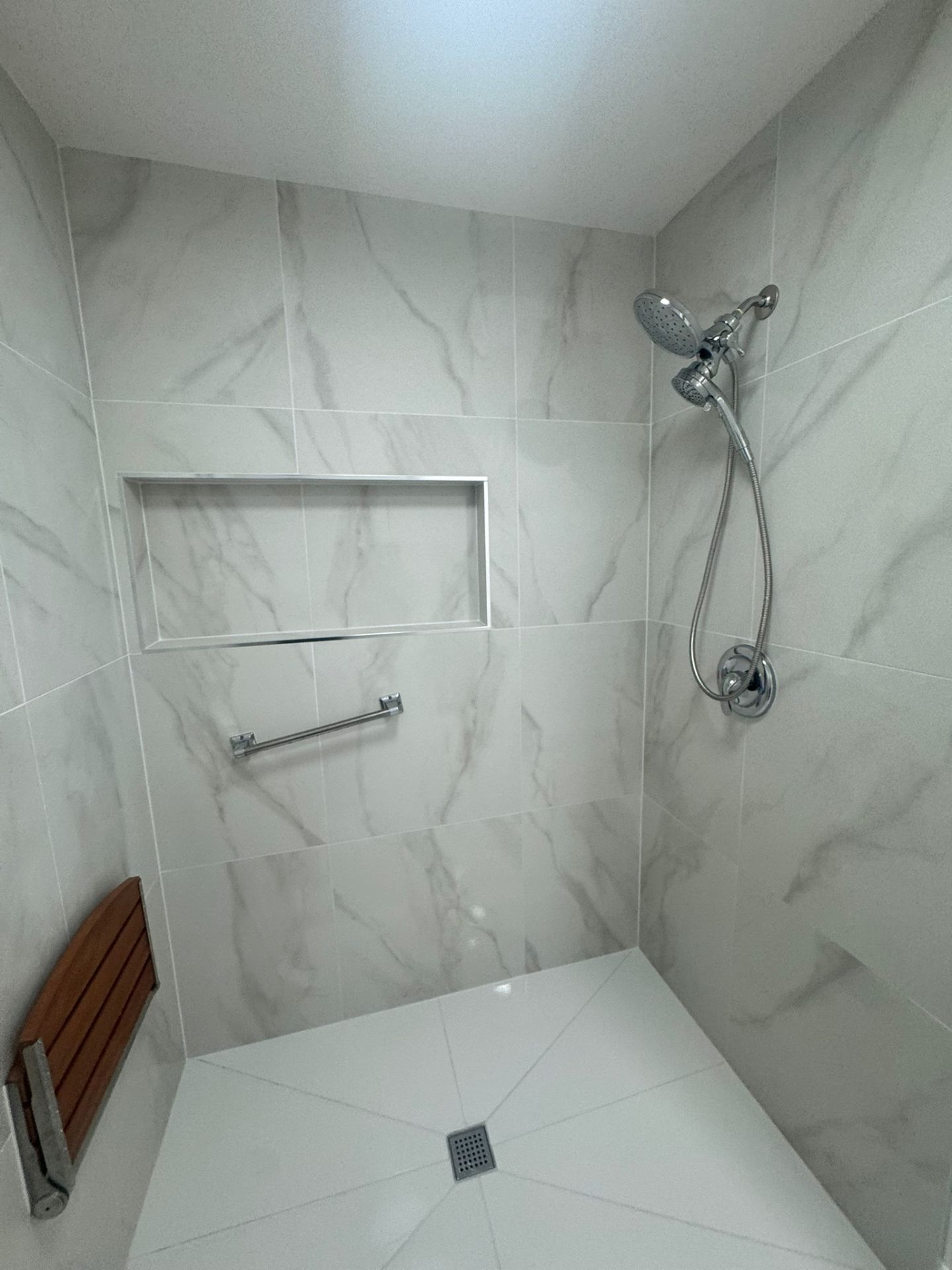 Walk-in shower with white marble tile and grab bar in Portland