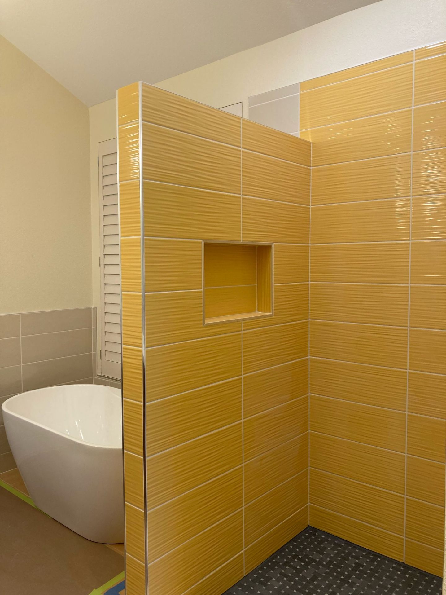 Yellow shower tile with built-in niche next to freestanding soaking tub in Portland